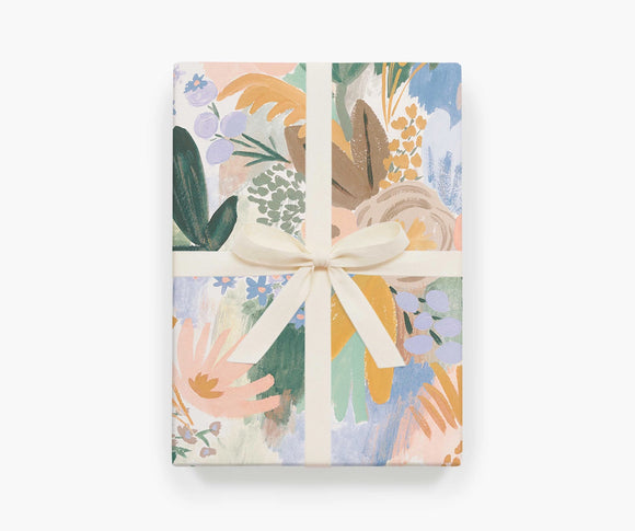 A single sheet of Luisa gift wrap by Rifle Paper Co, featuring soft painterly florals in pale pink, green, and mustard tones.