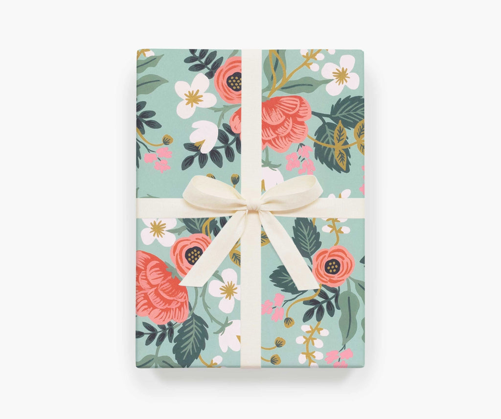 A present wrapped in the Birch wrapping paper by Rifle Paper Co, with a white ribbon tied around it with a bow