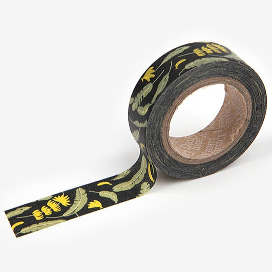 A roll of Daily Like washi tape, featuring banana tree leaves and yellow flowers on a black background