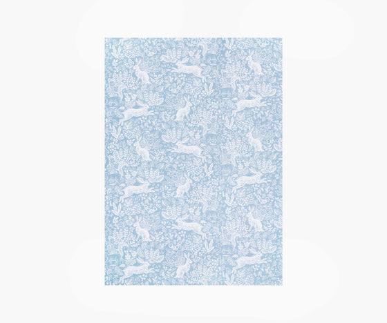 A single sheet of wrapping paper featuring the Fable design by Rifle Paper Co. This design features woodland animals in white on a soft blue coloured background.