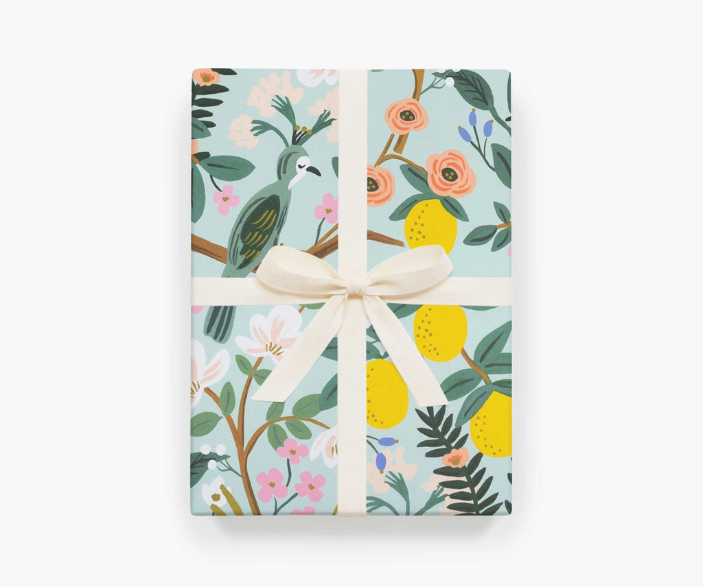A present wrapped in Shanghai Garden gift wrap by Rifle Paper Co, tied with a white ribbon